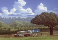 an old bus parked in the middle of a field with mountains in the back ground