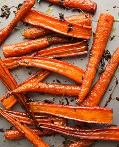 roasted carrots on a baking sheet with herbs and seasoning in the background text reads honey balsamie roasted carrots