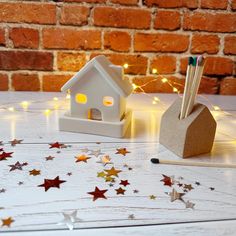 two small houses with pencils in them on a table next to some stars and lights