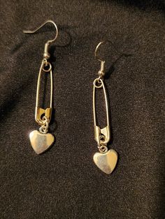 Safety pins on earring hooks, accented with solid heart charms, set of 2 earrings, silver tone, each measures about 2.5 inches.  Handmade, unisex jewelry.  Ready to ship. To continue shopping: http://www.rrrobinnn.etsy.com Diy Safety Pin Earrings, Paperclip Shaped Metal Earrings As Gift, Metal Safety Pin As Gift, Gift Safety Pin Shaped Single Earring, Silver Safety Pin Earrings As Gift, Safety Pin Shaped Earrings With Ear Wire, Silver Safety Pin Earrings For Gift, Silver Safety Pin Shaped Earrings For Gift, Everyday Metal Dangle Heart Earrings