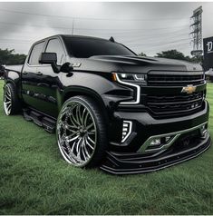 a black truck parked on top of a lush green field