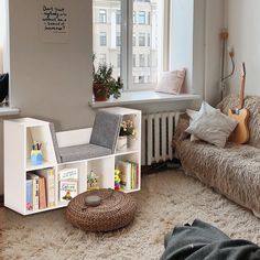 a living room filled with furniture and a book shelf next to a window on top of a shaggy rug