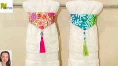 two white towels with colorful tassels hanging on a towel rack next to each other