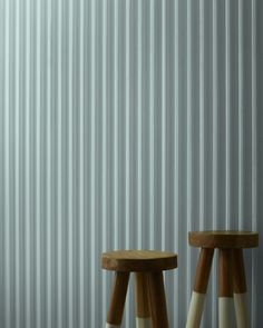 two wooden stools sitting next to each other in front of a wall with vertical blinds