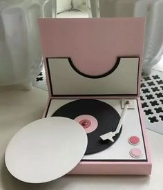 the record player is pink and white with a black disc in it's case