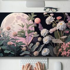 a person typing on a keyboard in front of a painting with flowers and a full moon