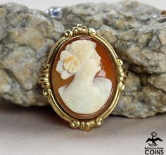 Metal: 10k Yellow Gold (.417)Weight: 6.1 gramsMeasurements: 1.56" Long; 1.27" Wide; 0.4" DeepShell: CarnelianMarkings: 10K*Delicately hand-carved, this beautiful carnelian shell cameo brooch features an image of a beautiful lady facing right with her hair up. The cameo of the woman is set into a lovely 10k yellow gold bezel. This outstanding Victorian cameo is in great condition, with light wear. The safety clasp works nicely. The stunningly bright carving gives the brooch that extra eye-appeali Formal Cameo Carnelian Jewelry, Formal Cameo Jewelry In Carnelian, Formal Carnelian Cameo Jewelry, Vintage Gemstone Brooches, Victorian Cameo, Buy Coins, Tacoma Wa, Gold Border, Carved Shell