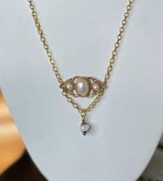 This lovely vintage gold and faux pearl brooch is reminiscent of the Sarah Coventry jewelry that was so popular in the late 60's and early 70's. It also has a Victorian vibe that is sweet and lovely. A pretty cut bezel glass bead was added as an extra bit of sparkle and dangles from a length of gold chain. This necklace has an 18" chain. Vintage Pearl Charm Jewelry For Anniversary, Vintage Jewelry With Pearl Charm For Anniversary, Elegant Gold Brooches With Pearl Pendant, Elegant Gold Necklace With Brooch, Vintage Pearl Gold Brooches, Vintage Gold Pearl Brooches, Gold Brooch With Pearl Pendant For Wedding, Gold Wedding Brooch With Pearl Pendant, Vintage Pearl Chain Jewelry For Anniversary