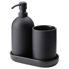 a black soap dispenser and cup sitting on a tray next to each other