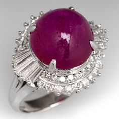 This spectacular ballerina ring is centered with one (1) oval cabochon cut star ruby set into a four-prong setting. The ruby is surrounded by thirty-eight (38) prong set round brilliant cut diamonds and ten (10) prong set tapered baguette cut diamonds. The ring measures 17.4mm at the top, rises 13.1mm above the finger, tapering to 2.9mm wide and 1.2mm thick at the base of the shank. It is currently a size 5.25. The ruby has a few surface reaching inclusions but this is common for the stone and does not take away from its beauty at all. Diamond Ballerina Ring, Antique Engagement Rings Sapphire, Ballerina Ring, Estate Jewelry Rings, Ruby Set, Wedding Ring Diamond Band, Vintage Star, Baguette Cut Diamond, Star Ruby