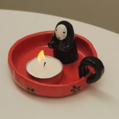 a red tray with a candle and a black cat figurine on it