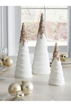 three white christmas trees sitting on top of a table next to plates and silverware