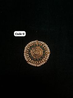 a gold brooch with green and white stones in the center on a black background