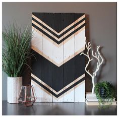 some plants are sitting on a table next to a wooden paneled wall with an arrow pattern