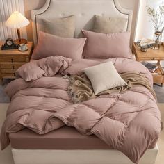 an unmade bed with pink comforter and pillows