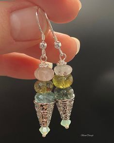 Indulge in the mesmerizing beauty of these Multicolor Gemstone Dangle Drop Earrings. Perfect for someone who loves to make a statement with their accessories, these earrings feature a mix of natural quartz, heated aquamarine, aventurine, and Swarovski crystals in shades of green and blue. The silver plated components add a touch of elegance to the tribal/boho style design. The total length of these earrings is 4cm, making them a great addition to any outfit. These earrings are not only eye-catching but also versatile, making them a perfect gift for her. Let her embrace her unique sense of style with these beautiful and natural gemstone earrings. Please note that the dimensions, colors, and patterns of natural gemstones may vary slightly, making each pair of these earrings one-of-a-kind. Ad Multicolor Dangle Earrings With Gemstone Accents, Multicolor Gemstone Accented Drop Earrings, Fusion Style Dangle Earrings With Gemstone Accents, Fusion Style Dangle Earrings For Jewelry Making, Fusion Style Dangle Jewelry For Jewelry Making, Green Dangle Stone Jewelry, Green Dangle Jewelry With Stones, Fusion Style Natural Stone Drop Earrings, Fusion Style Dangle Jewelry With Natural Stones