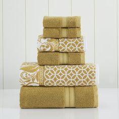 four towels stacked on top of each other in yellow and white colors with an intricate design