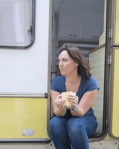 a woman sitting on the side of a train holding a cup