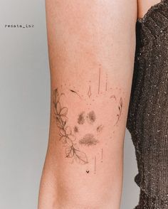 a woman's leg with a tattoo on it that has flowers and leaves drawn on it