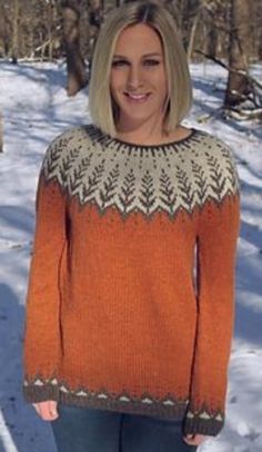 a woman standing in the snow wearing an orange sweater