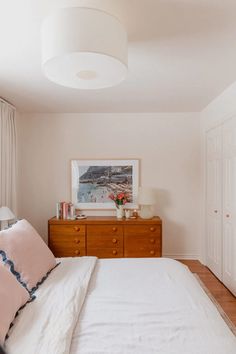 a bedroom with a bed, dresser and pictures on the wall above it's headboard