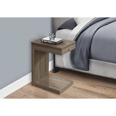 a bed sitting next to a night stand on top of a wooden floor