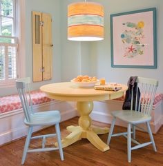 a table with two chairs around it and a lamp on the wall above it in front of a window