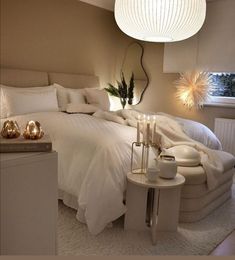 a white bed sitting in a bedroom next to a lamp on a table and chair