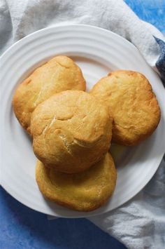 three biscuits on a white plate next to a blue towel