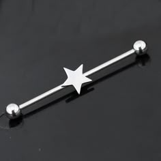 a metal bar with a white star on the top and silver balls around it, sitting on a black surface