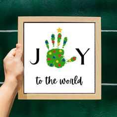 a person holding up a framed sign with the word joy to the world written on it