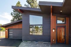 a house with two garages and windows on the side of it in front of some trees