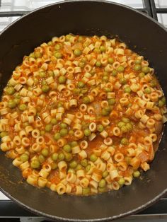 a pan filled with pasta and peas on top of a stove