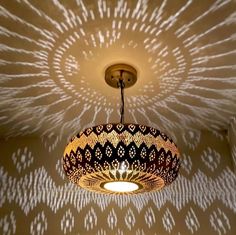 a light fixture hanging from the ceiling in front of a wallpapered background with white circles