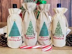 three wine bottles with christmas trees on them and candy canes in front of it