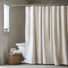 a white bath tub sitting under a window next to a shower curtain and towel rack