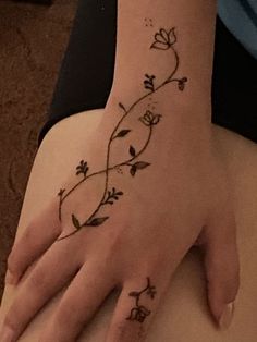 a woman's hand with tattoos on it and flowers on the wrist is shown