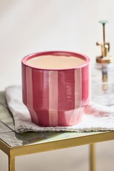 a pink cup sitting on top of a table next to a gold faucet