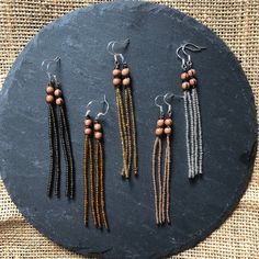 five different beaded earrings on a black stone plate with burlian beads hanging from them