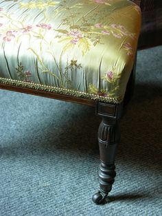 the foot stool is made from wood and has floral upholstered fabric on it