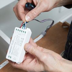 two people are working on an electronic device with wires attached to the back of it