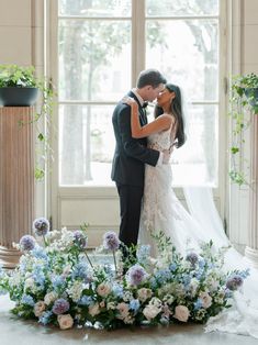 a bride and groom kissing in front of a window