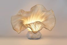 a large white flower sitting on top of a table next to a light bulb in the shape of a vase