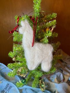 a white llama ornament hanging from a christmas tree