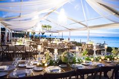 an outdoor dining area with tables and chairs set up for formal dinner overlooking the ocean