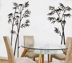 a glass table with four chairs and a wall sticker that has bamboo trees on it