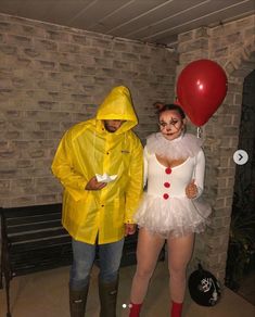 two people dressed in costumes standing next to each other and one holding a red balloon