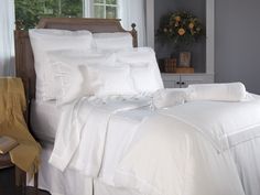 a bed with white sheets and pillows in a room