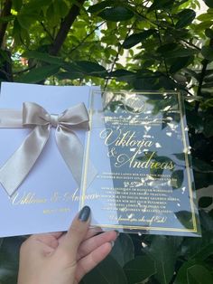 a person holding up a wedding card with a bow on it's front and back