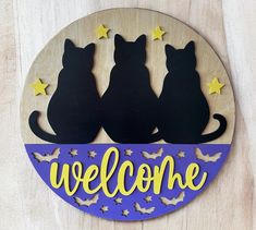 a wooden sign with two cats sitting on it's back and the words welcome